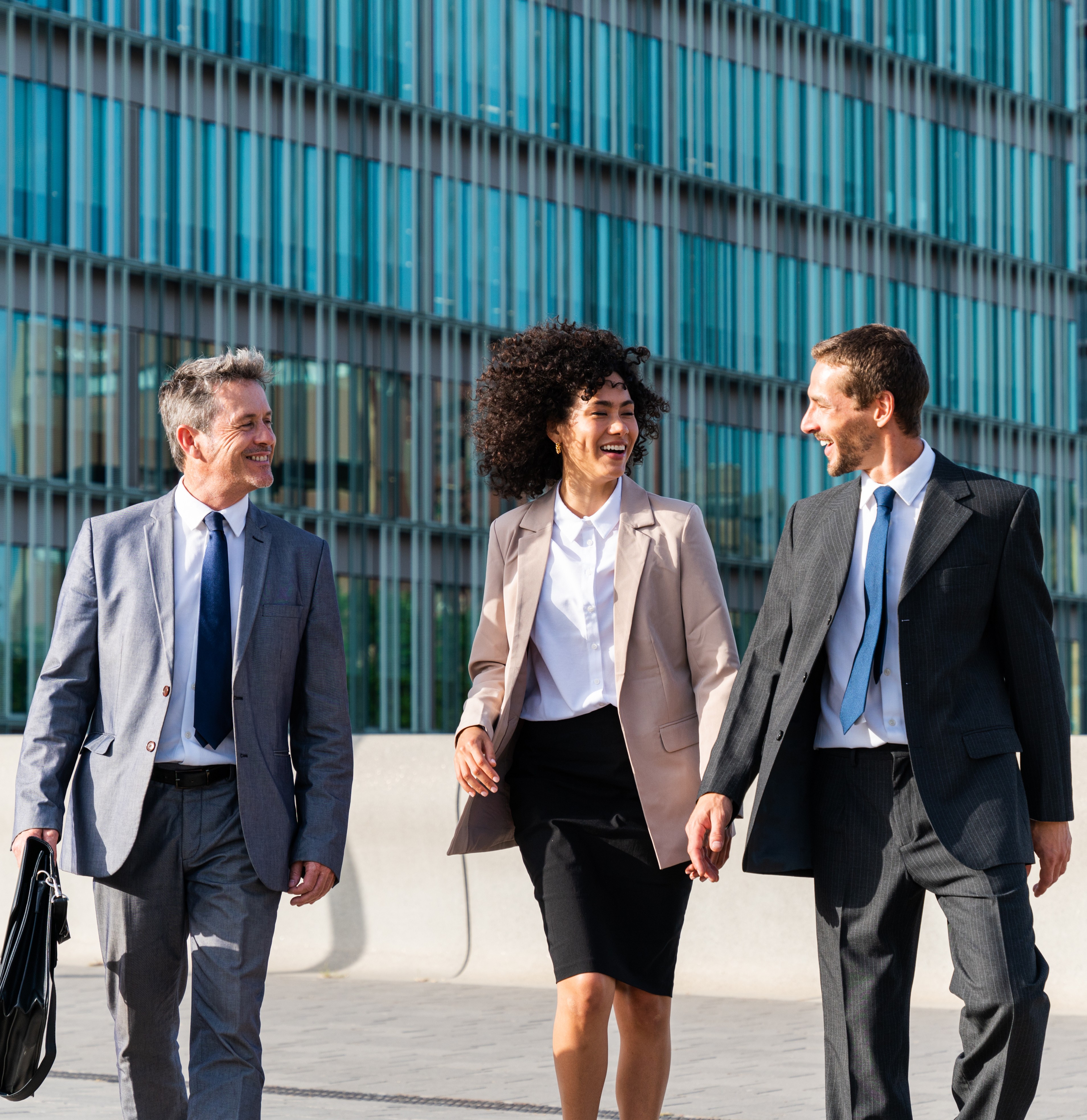 three professionals walk outside large building